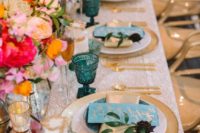 a beautiful summer wedding tablescape with a printed tablescape, gold chargers and cutlery, bright blooms and candleholders