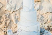 a beautiful white and watercolor blue wedding cake with a gold edge, a coral on top is amazing for a beach wedding
