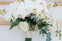 a beautiful white wedding bouquet of orchids and roses, with some greenery is classics