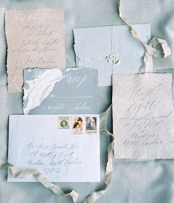 a beuatiful and chic wedding invitation suite with light blue envelopes, a blue RSVP, neutral pieces with botanical prints