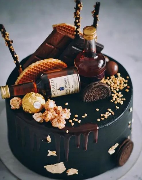 a black wedding cake with chocolate drip, mini alcohol bottles, waffles, chocolate, popcorn and nuts is a delicious-looking idea