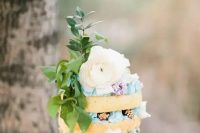 a boho naked wedding cake with blue cream, gilded blackberries, a large bloom and foliage