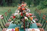 a bold dramatic summer wedding tablescape with a teal tablecloth, pink napkins, bright blooms and greenery and bold candles
