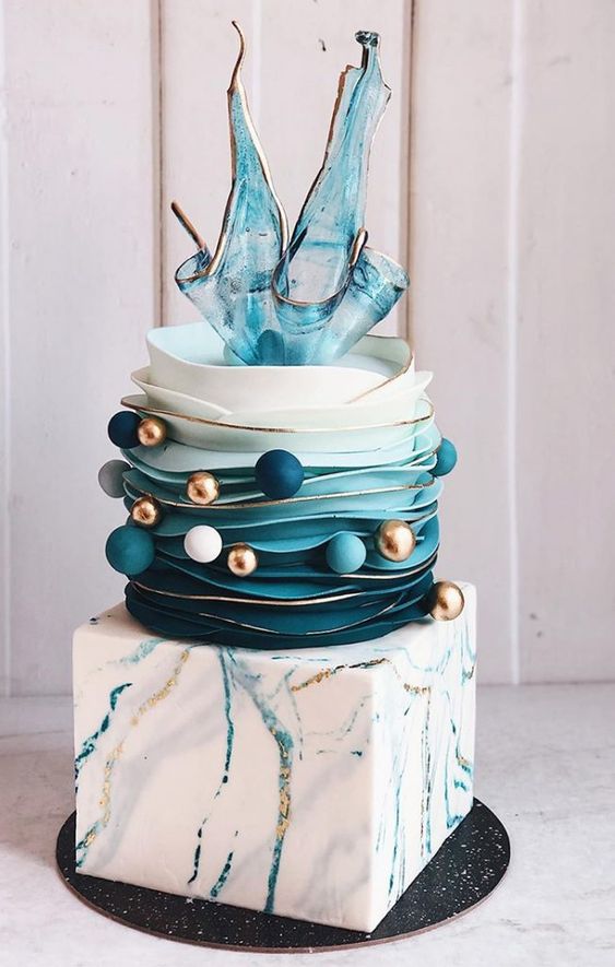 a bold modern wedding cake with a square first tier with splatters, a ruffle tier with spheres and turquoise shards on top