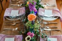 a bold summer wedding tablescape with pink napkins, super bright florals, geodes and purple candles