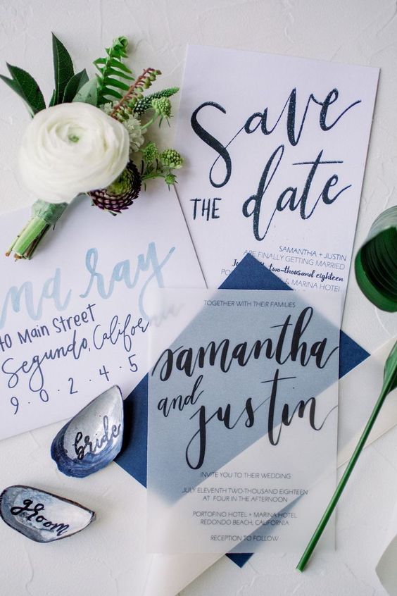 a bright and cool coastal or seaside wedding invitation suite in white and navy, with light blue and navy calligraphy and a navy envelope