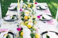 a bright contasting summer wedding table with black and white plates, yellow and white candles, dip dyed napkins and yellow blooms