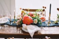 a bright summer wedding table with a blue runner, bright florals, colorful candles and white napkins