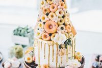 a cheerful boho wedding cake with a whole tower of usual and mini donuts, with gold drip and fresh blooms is a very whimsical idea