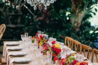 a chic and refined summer wedding tablescape with bold blooms, crystal chandeliers, neutral linens