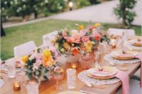 a chic summer wedding table with pink and yellow blooms, with pink napkins, yellow porcelain and gold touches