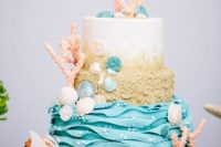 a colorful wedding cake with a white, beach sand and blue wave tier, seashells, corals, bubbles is a stunning idea for a beach wedding
