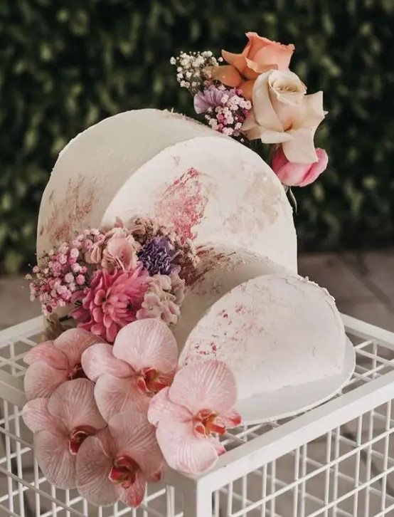 a double cake top forward wedding cake in neutrals with watercolors, with pink, purple and blush blooms for a refined spring or summer wedding
