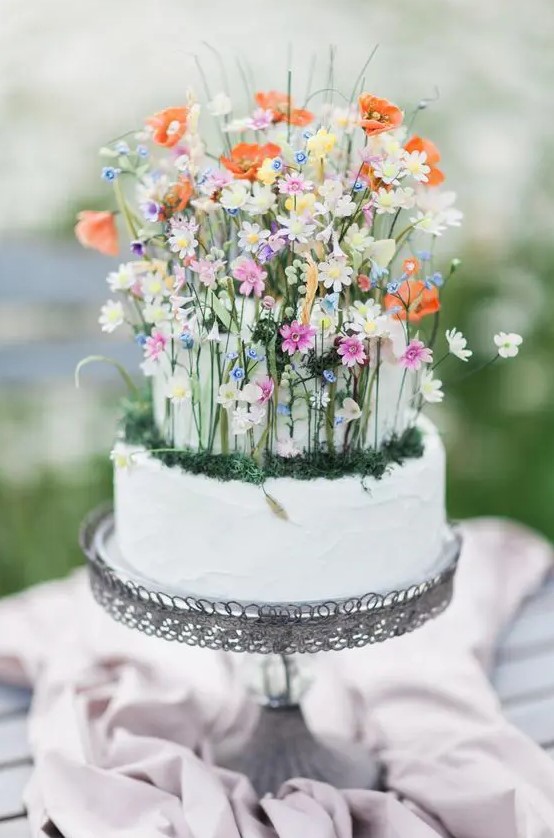 a fantastic wedding cake in white, with tiny colorful flowers, moss and foliage is a lovely idea for a secret garden wedding
