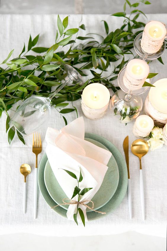 a fresh neutral summer wedding table with birch wrapped candles, green plates, white cutlery and greenery