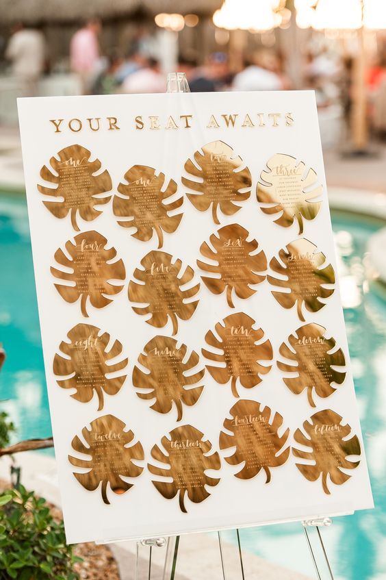 a glam tropical seating chart done with gilded monstera leaves is a chic and bright idea with a shiny touch