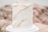 a light blue watercolor covered wedding cake with a gold edge and gold leaf is a very ethereal wedding idea