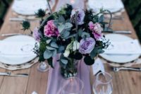 a lilac fabric runner, a bouquet of lilac and pink blooms plus greenery and thistles for a beautiful tablescape