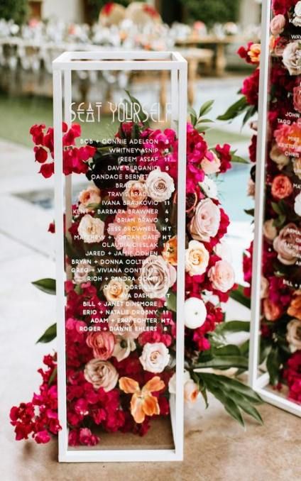 a modern seating chart with glass cubes and bright blooms and greenery is a cool idea for a floral-filled wedding