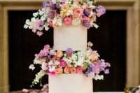 a modern white wedding cake with super bright and blush blooms between the tiers looks wow