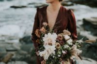 a moody textural wedding bouquet of fresh and dried blooms, dried foliage and herbs plus orange ribbons