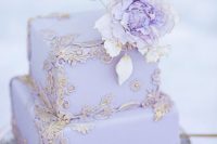 a refined lilac wedding cake with chic 3D gold patterns and some matching sugar flowers on the top