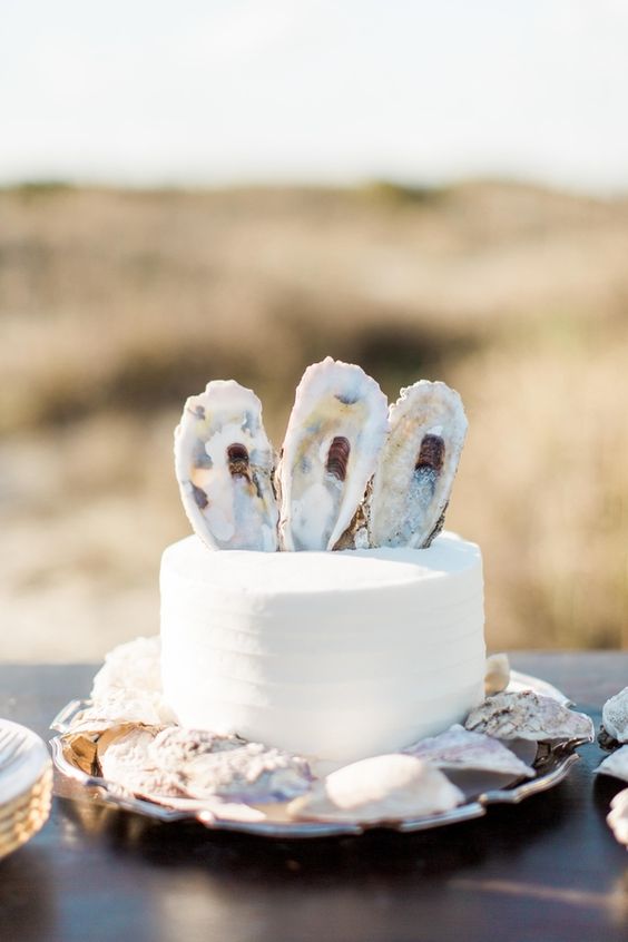 a romantic beach wedding cake in white, with sugar seashells and pearls is a lovely and chic idea
