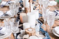 a rustic beach wedding table with a blue runner, pillar candles, wooden candleholders and seashells is a fresh take on traditions