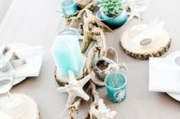a rustic beach wedding tablescape with driftwood, starfish, bright turquoise candles and vases with succulents plus wood slice coasters