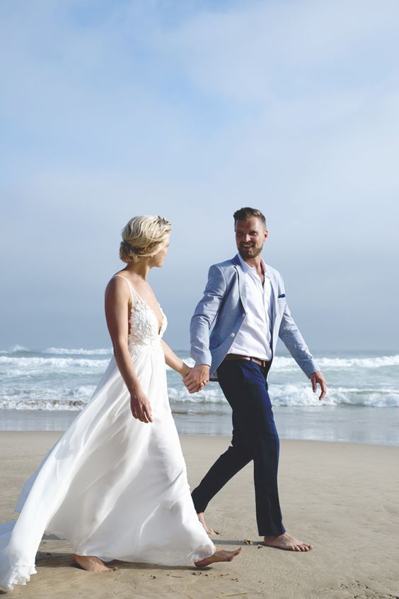 a sea inspired groom's outfit with a light blue jacket, navy pants, a white shirt and no tie