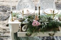 a seaglass colored tablescape with air plants, greenery, pink blooms, tall candles and an airy light green runner