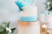 a stylish beach wedding cake with blue watercolor and copper ombre, with shiny blue waves on top