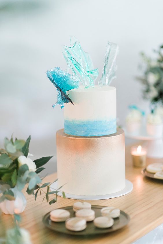 a stylish beach wedding cake with blue watercolor and copper ombre, with shiny blue waves on top