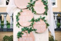 a stylish wedding seating chart made of plywood circles and greenery is a stylish and chic idea