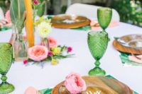 a super bold summer wedding tablescape with printed chargers, pink napkins and blooms and green glasses