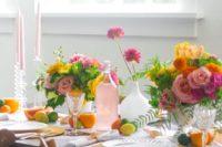 a super bright summer citrus tablescape with bold blooms, pink candles, yellow chargers and citrus right on the table