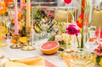 a super bright summer wedding tablescape with bright glass placemats, colorful blooms and candles, gold candleholders and bright napkins