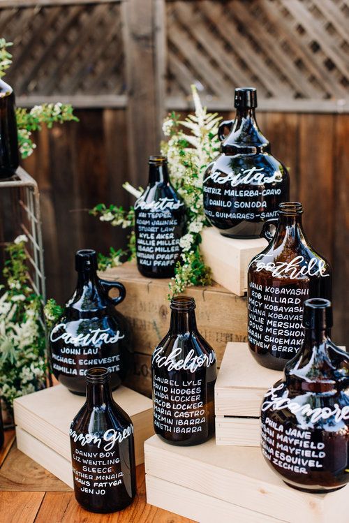 a super creative wedding seatign chart composed of large glass bottles is a cool idea for a vineyard wedding