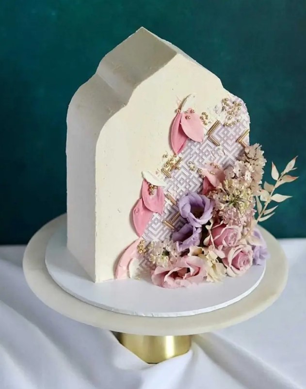 a top forward wedding cake inspired by Middle Eastern Architecture, with pink petals, gold pearls, dried grasses and fresh blooms for a Moroccan wedding