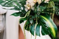 a tropical beach wedding bouquet with large tropical leaves and greenery plus neutral blooms