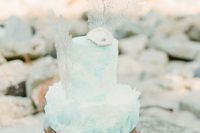 a turquoise watercolor textural wedding cake topped with corals and seashells just screams beaches