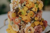 a unique one tier wedding cake with pink, rust, yellow and mustard blooms, dried and fresh, a yellow topper