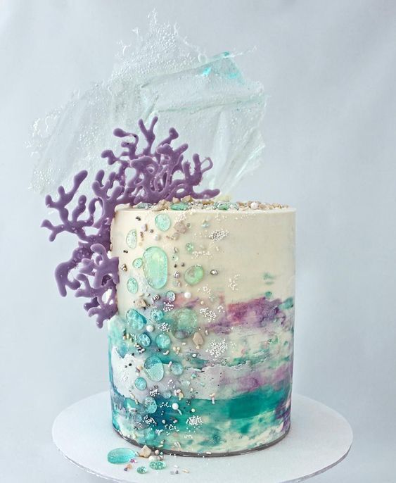 a vibrant beach wedding cake with teal, turquoise, purple brushstrokes, corals, sea splashes and bubbles looks really bold