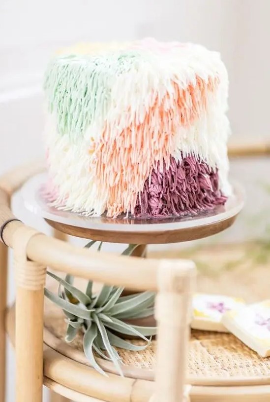a whimsical wedding cake with color block yarn-like decor for a 70s wedding is a lovely idea with a strong boho feel