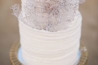 a white textural wedding cake with pink corals will be a lovely option for a coastal or a beach wedding