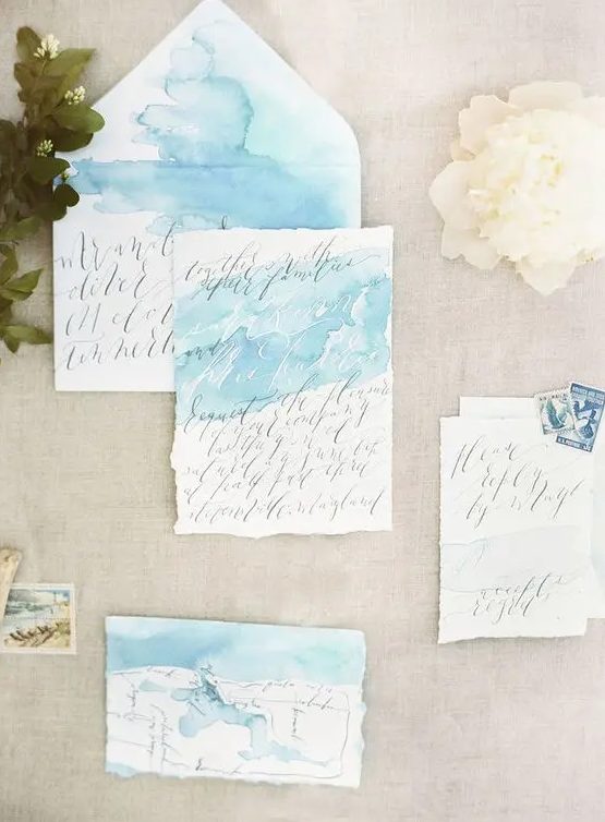 airy light blue watercolor wedding invitations with calligraphy and a raw edge for a seaside wedding