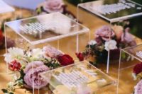an acrylic riser seating chart with bright blooms and greenery is a chic and stylish idea for a modern wedding