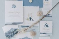 an ocean blue wedding invitation suite with navy and blue watercolors on the pieces, monograms and coral and seashell prints plus white seals