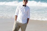 tan shorts, a white shirt, a black bow tie and stylish sunglasses for a relaxed and comfy look