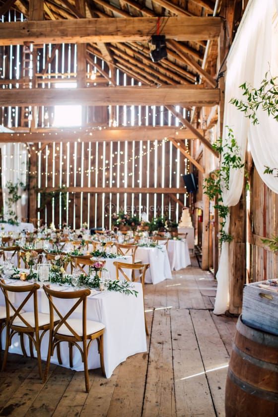 a barn wedding reception space with lights, greenery, bold blooms, barrels is a chic and airy wedding space